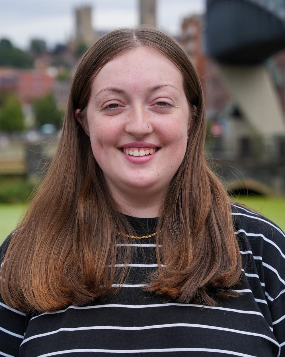 A smiling member of the Identity Agency team, photographed by the waterfront with Lincoln Cathedral behind.